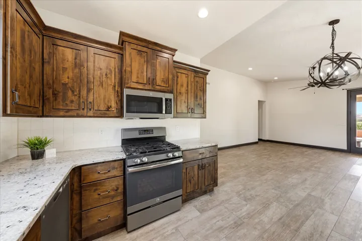 Kitchen featuring wood cabinetry, stainless steel appliances, light-toned countertops, and a white subway tile backsplash