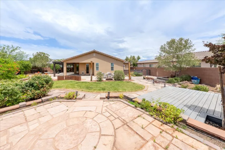 Expansive backyard featuring a circular paver patio, a green lawn area, and a covered patio structure