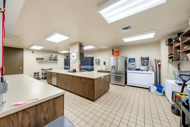 Spacious kitchen featuring extensive counter space, wood-finish cabinetry, stainless steel appliances, tile flooring, and ample overhead lighting