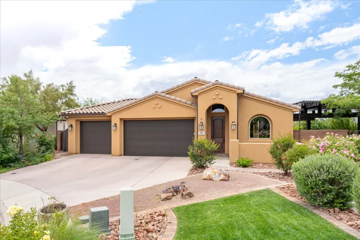 Stucco exterior with a tiled roof, featuring a two-car garage, arched entry, and an arched window