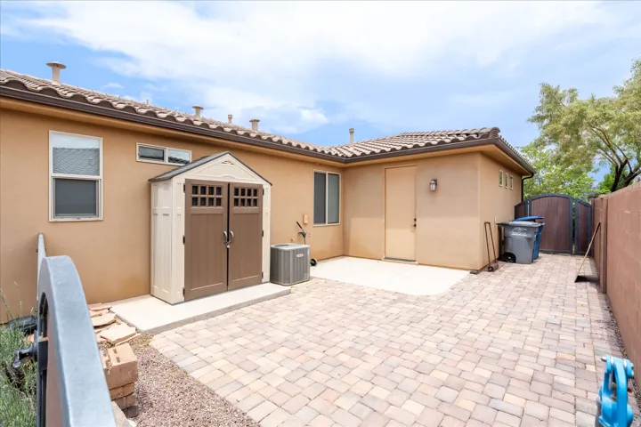 Expansive paver patio with a stucco exterior and tiled roofline