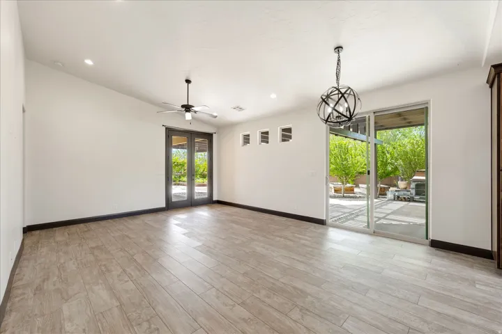 Spacious interior room featuring wood-finish flooring, a contemporary ceiling fan, and recessed lighting