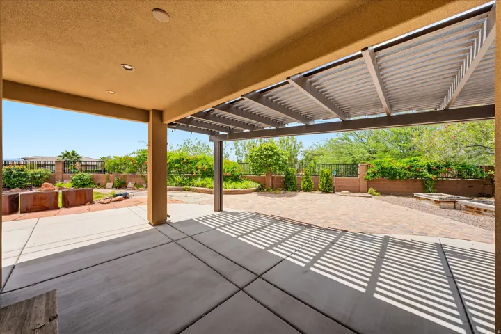 Expansive outdoor patio featuring a covered concrete area, an open paver patio, and an adjustable louvered pergola