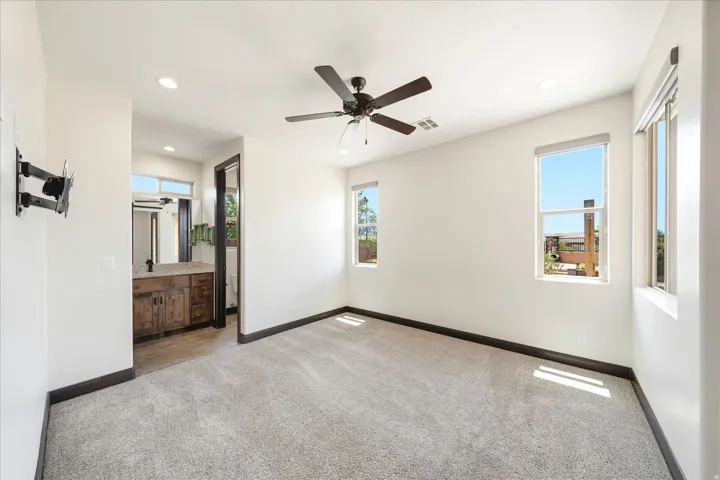 Carpeted room with a dark wood-finish ceiling fan and two windows