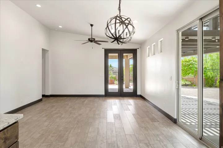 Spacious interior featuring wood-finish flooring, a contemporary ceiling fan, and a sculptural orb chandelier