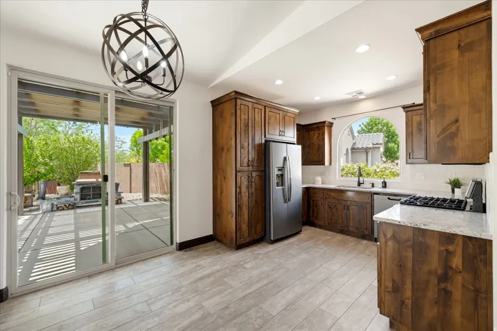 Kitchen featuring wood cabinetry, stainless steel appliances, granite countertops, and a white subway tile backsplash