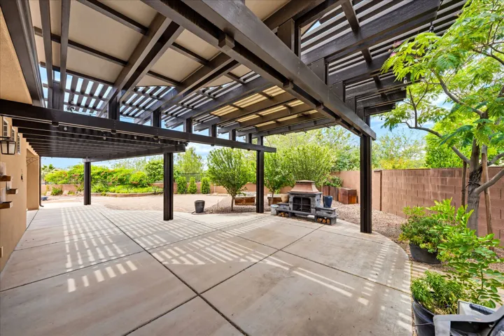 Expansive outdoor patio featuring a wood pergola with partial shading and a built-in outdoor fireplace