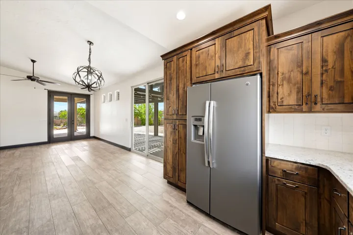 Kitchen and dining area featuring wood-finish flooring, dark wood cabinetry, a stainless steel side-by-side refrigerator, and a white tile backsplash