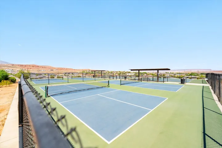 Community courts featuring multiple blue and green playing surfaces, chain-link fencing, and shaded structures