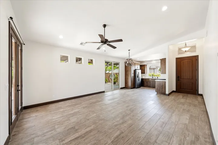Expansive open-concept living area featuring wood-finish flooring, recessed lighting, and a dark wood ceiling fan
