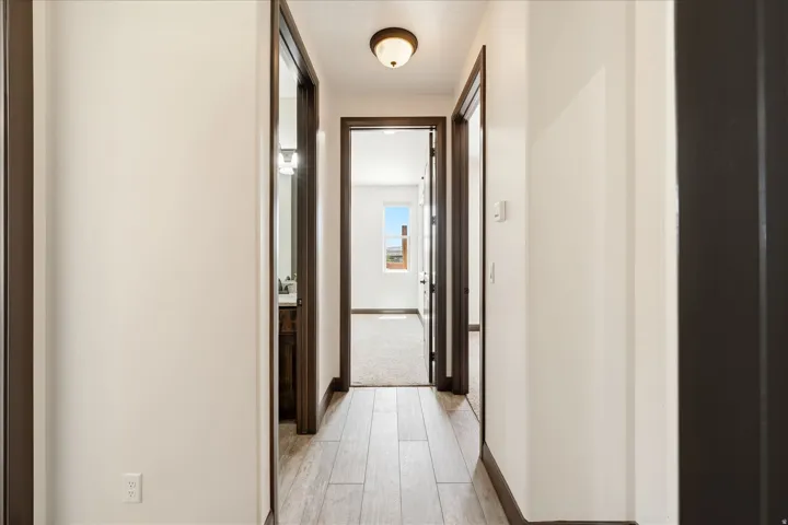 Hallway with wood-finish tile flooring, recessed ceiling light fixture, and dark trim