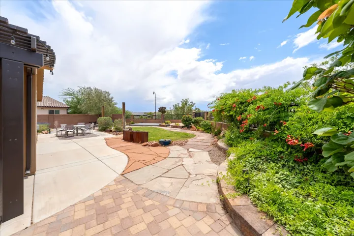 Outdoor living space featuring a concrete patio, a stone pathway, and lush landscaping with flowering vines