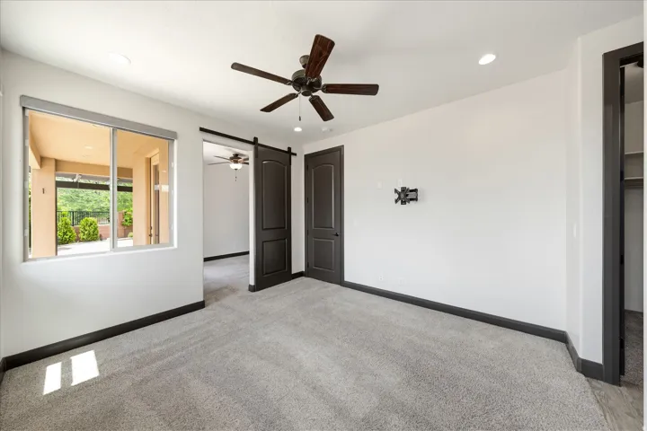 Carpeted interior room featuring a large window, dark trim, recessed lighting, and a ceiling fan