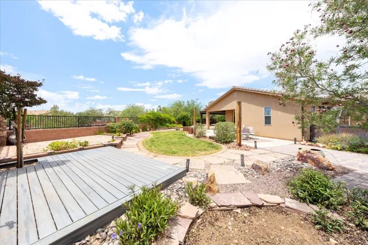 Expansive backyard featuring a composite deck, a stone patio, and a central grass area