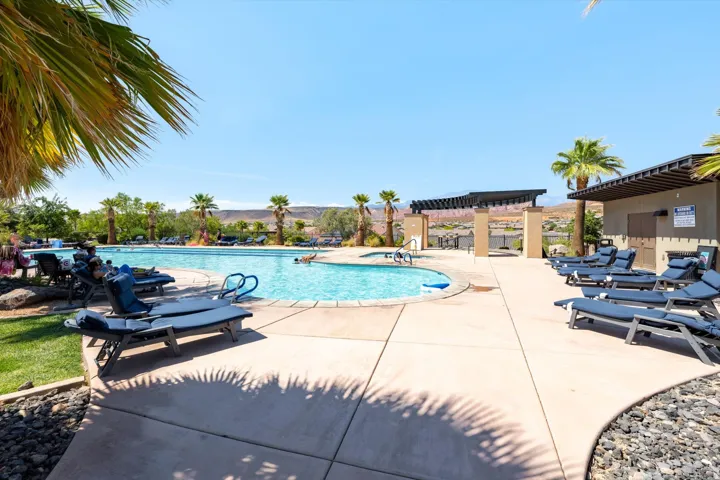 Expansive outdoor community pool featuring a curved design, adjacent hot tub, and surrounding concrete deck