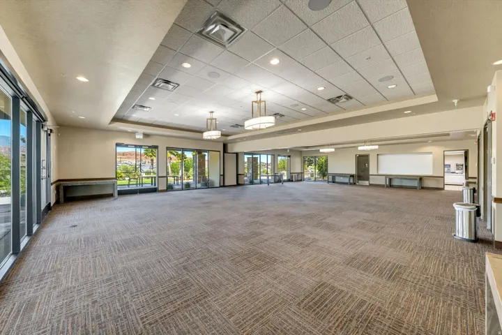 Spacious multi-purpose room featuring textured carpet flooring, recessed lighting, and large sliding glass doors