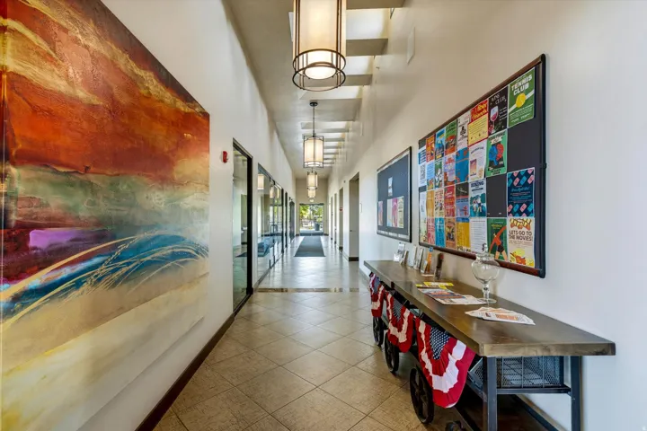 Long hallway featuring geometric tile flooring, recessed lighting, glass-paneled walls, and built-in bulletin boards