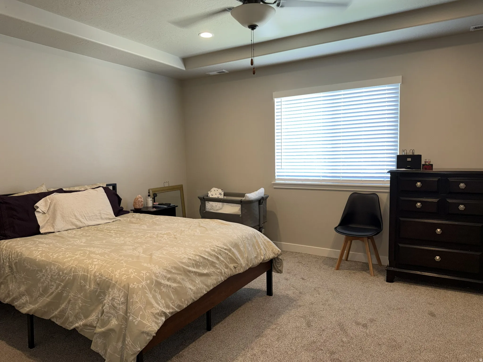 Carpeted room featuring a tray ceiling with recessed lighting and a ceiling fan