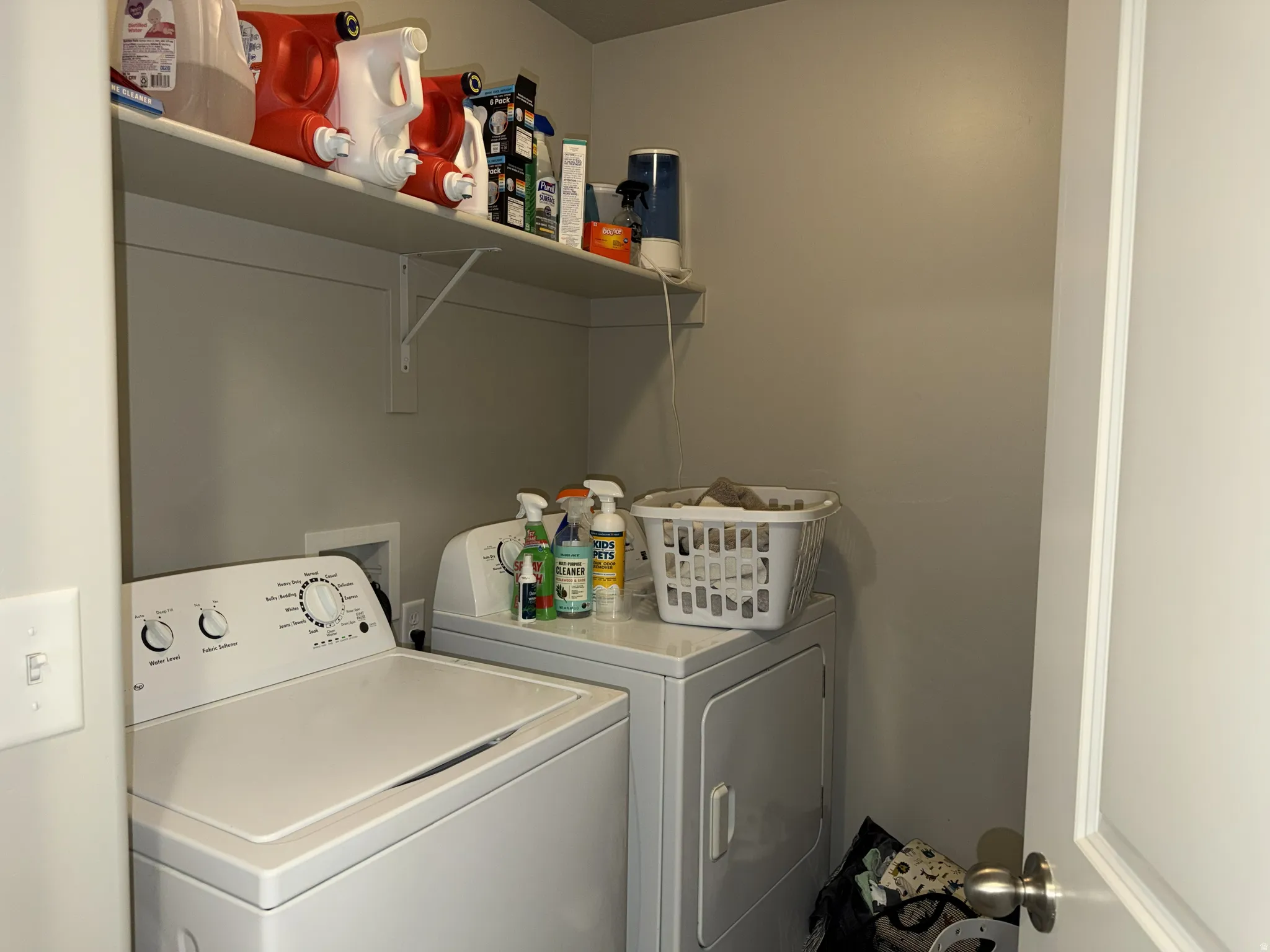 Dedicated laundry area featuring a white top-load washing machine, a white front-load dryer, and an upper wall-mounted shelf