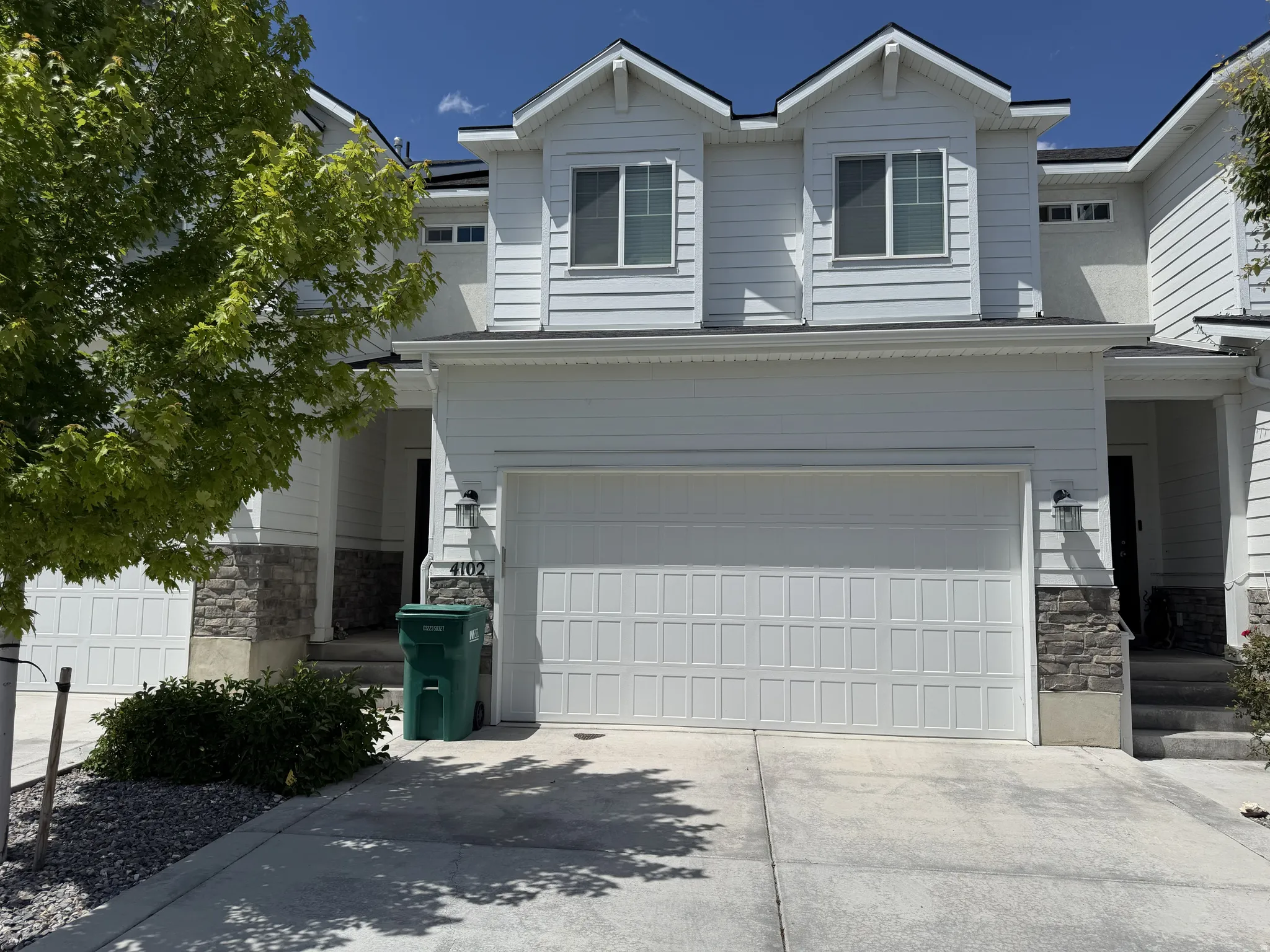 Modern white siding exterior featuring stone veneer accents, multiple windows, and an integrated garage