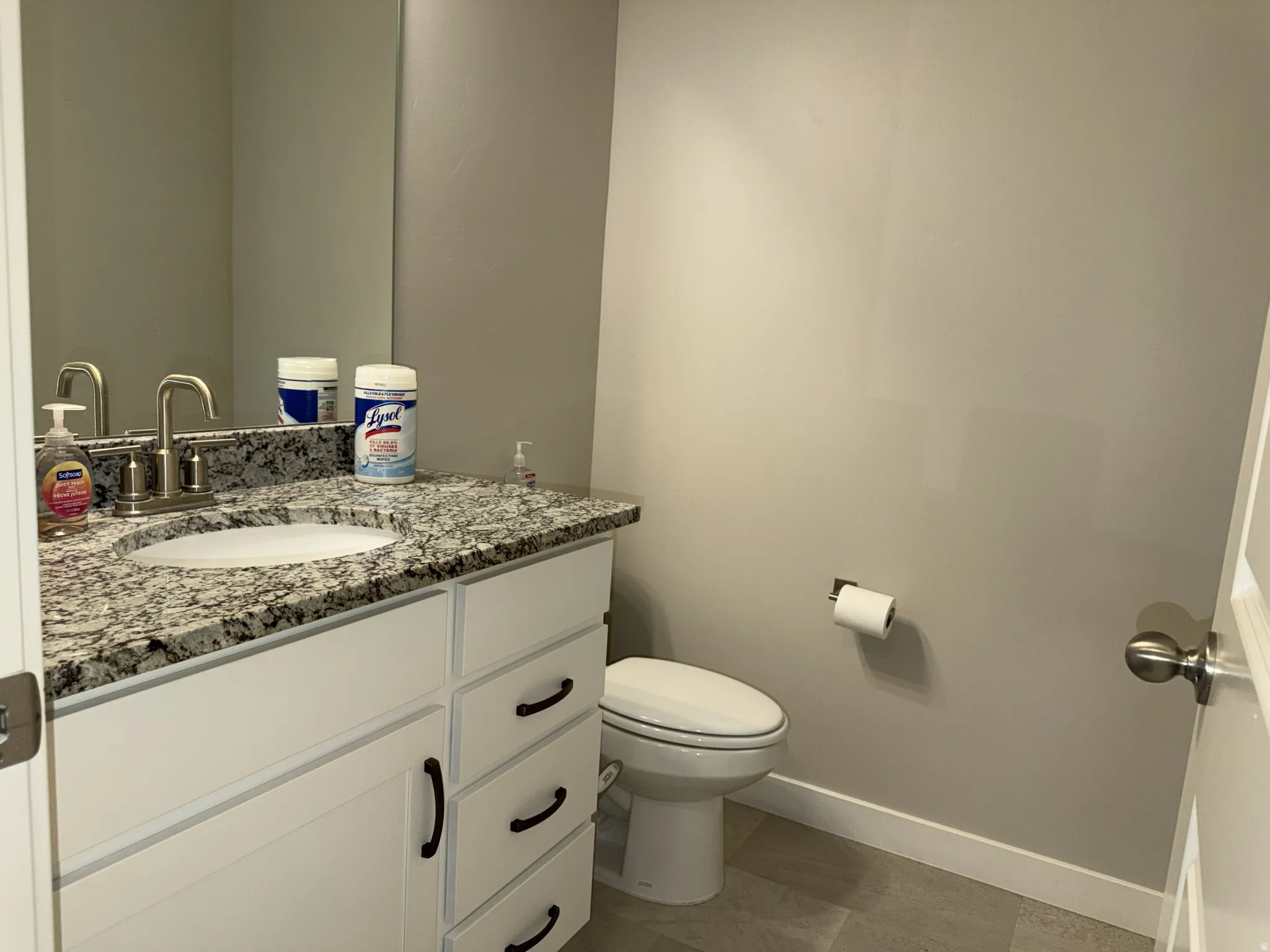 Bathroom featuring a white vanity with paneling and black hardware, a speckled countertop, an undermount sink, and a brushed nickel faucet