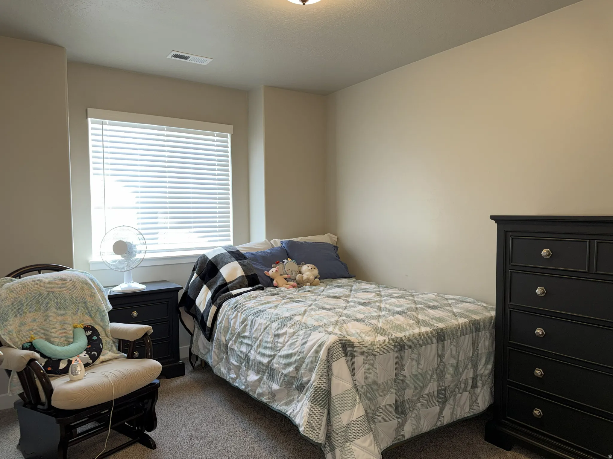 Bedroom featuring a single window with blinds, light neutral walls, and a ceiling light fixture