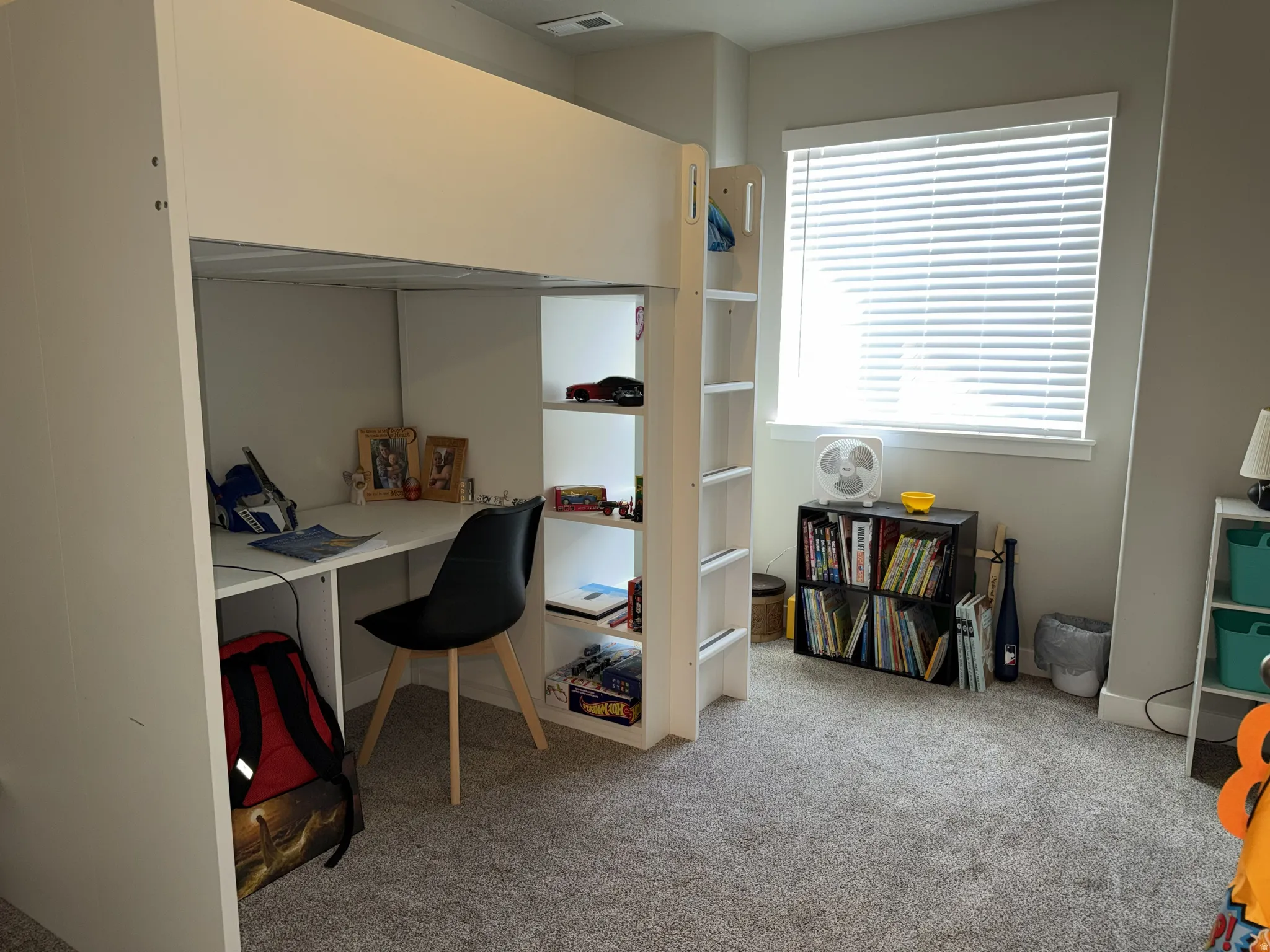 Carpeted interior room featuring a large window with horizontal blinds, light gray wall paint, and white trim