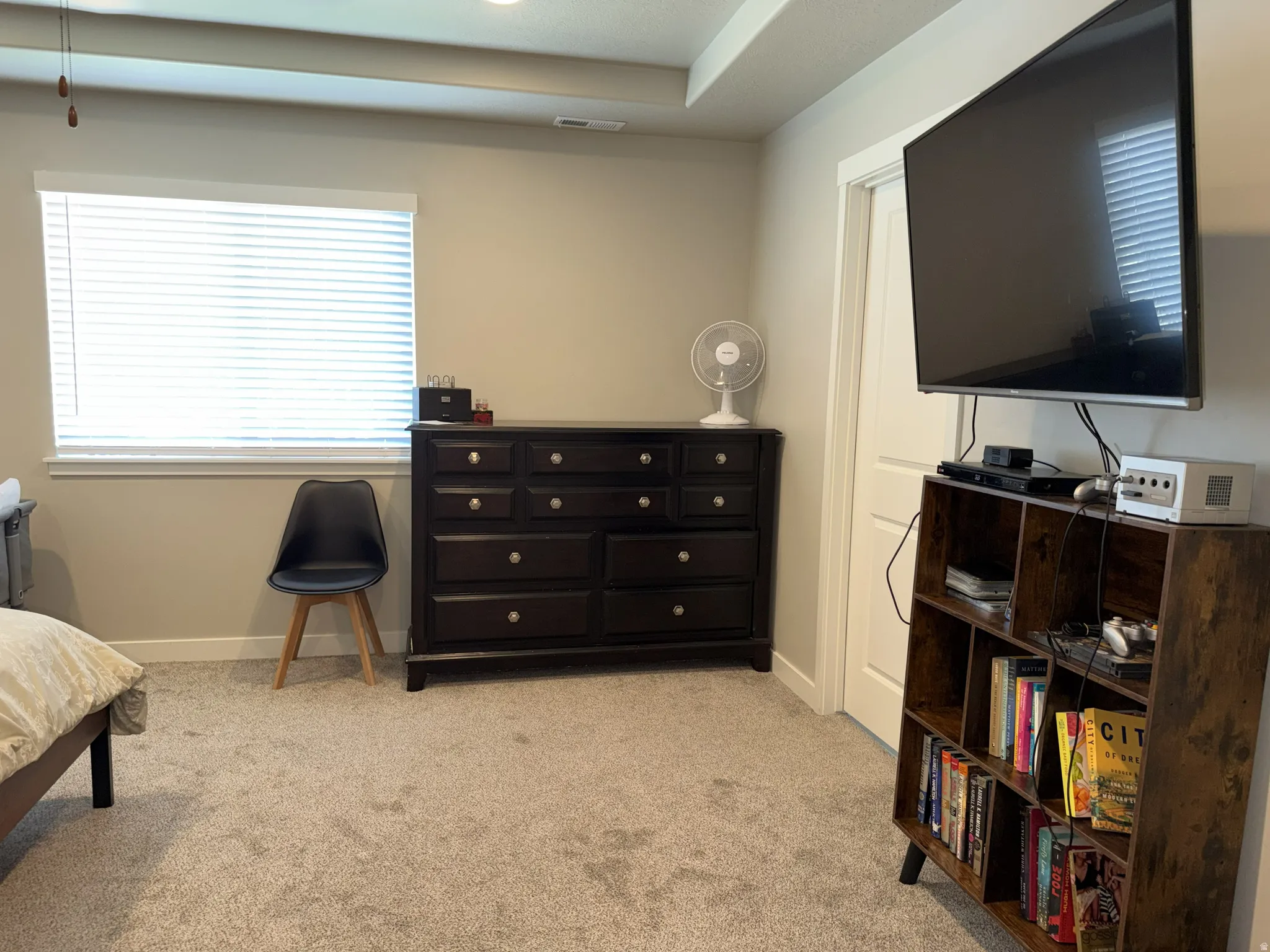 Neutral-toned carpeting extends throughout this room, featuring a white window with horizontal blinds