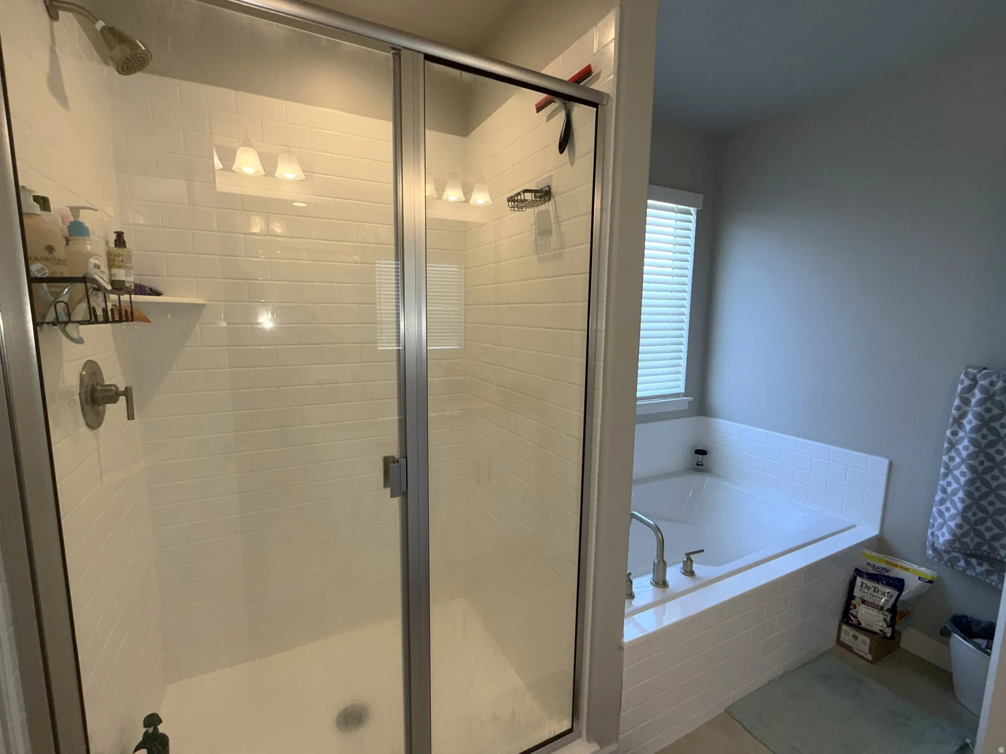 Shower with subway tile surround and integrated shelf, featuring a glass enclosure
