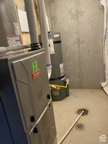 Bryant furnace and a water heater, positioned on a concrete floor with visible drains