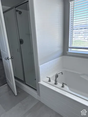 Bathroom featuring a built-in tub with subway tile surround, brushed nickel fixtures, and a window with horizontal blinds
