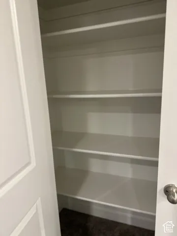 Built-in shelving with multiple levels, painted white finishes, and textured carpeting