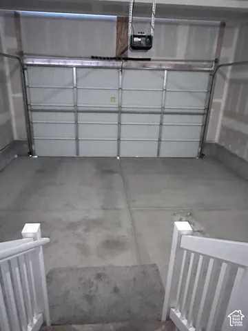 Attached garage with concrete flooring, automatic garage door opener, and white paneled garage door