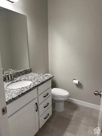 Bathroom featuring a single vanity with a white cabinet base, speckled countertop, and an undermount sink