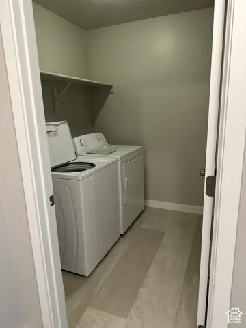 Dedicated utility closet featuring a built-in shelf, light gray walls, white baseboards, and wood-finish flooring