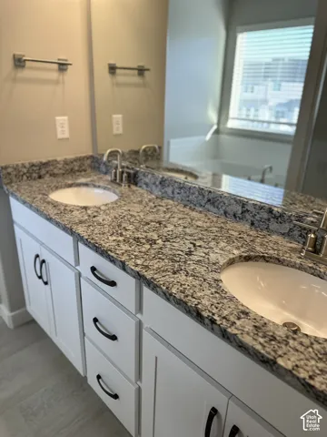 Dual undermount sinks set into a speckled countertop, complemented by white cabinetry with black hardware