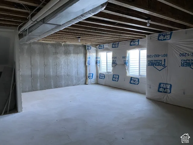 Unfinished lower level with concrete flooring, exposed ceiling joists, three egress windows, partially insulated walls, and exposed ductwork