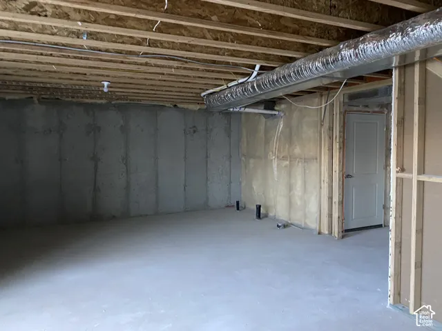 Unfinished basement space featuring exposed wood joists, concrete foundation walls, and a concrete floor