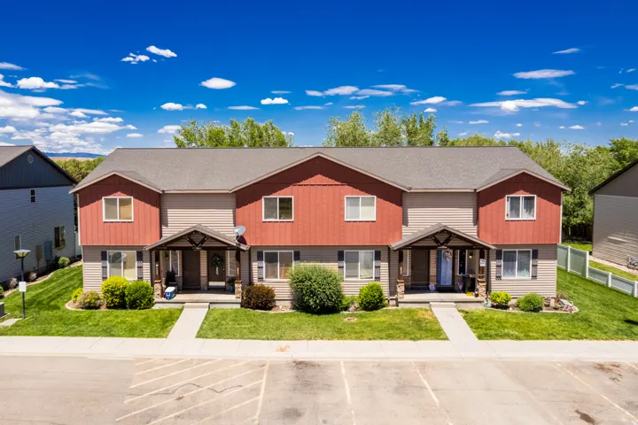 Two-story multi-family residence with a neutral siding and red-toned board and batten facade