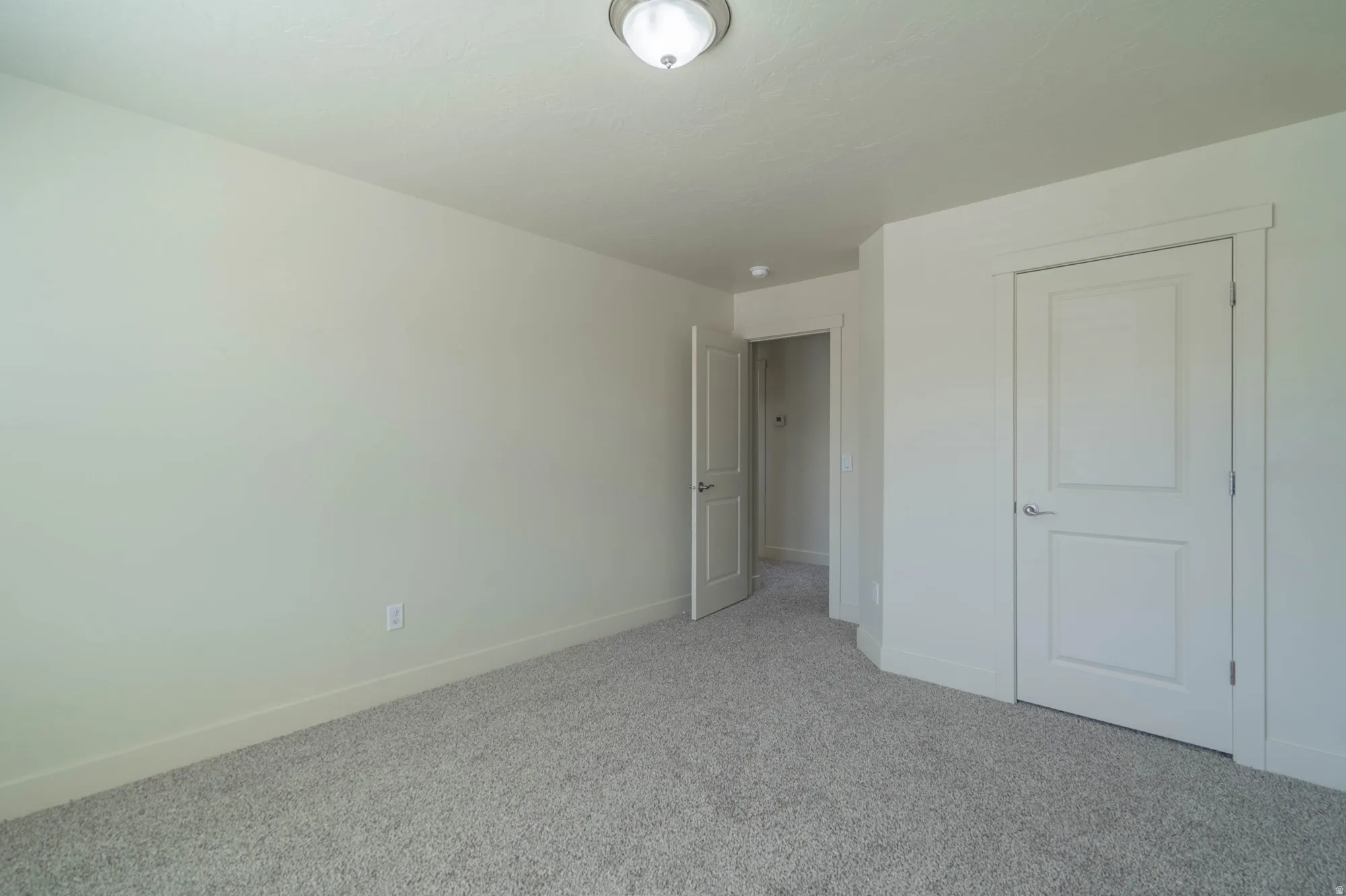 Neutral-toned room with light gray carpet flooring and white baseboards