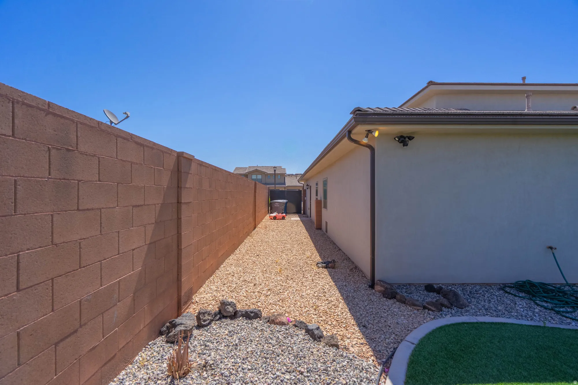 Side yard featuring a gravel pathway, stucco exterior, and concrete block wall