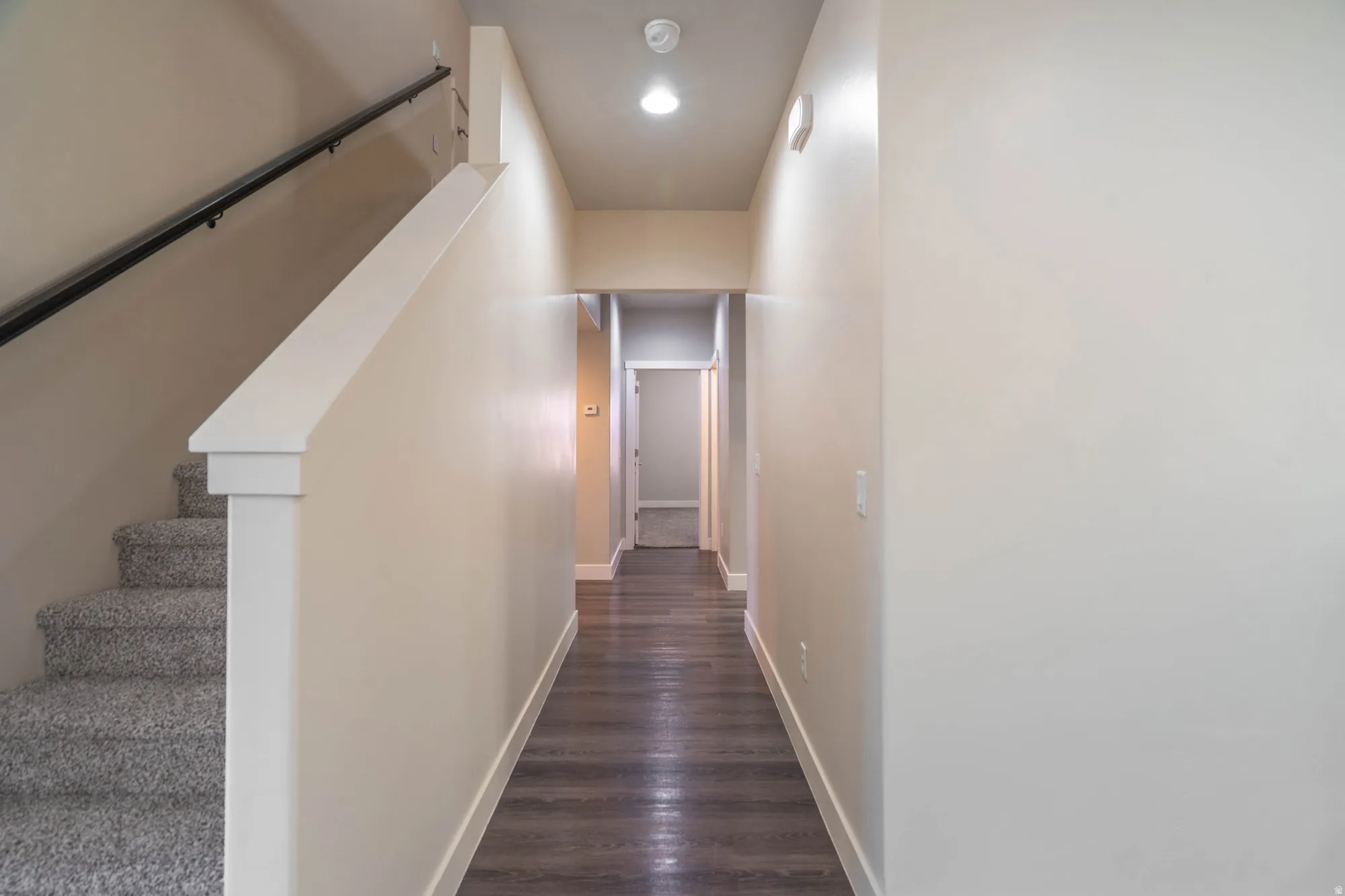 Entryway featuring wood-finish flooring, recessed lighting, and a carpeted staircase with a dark railing