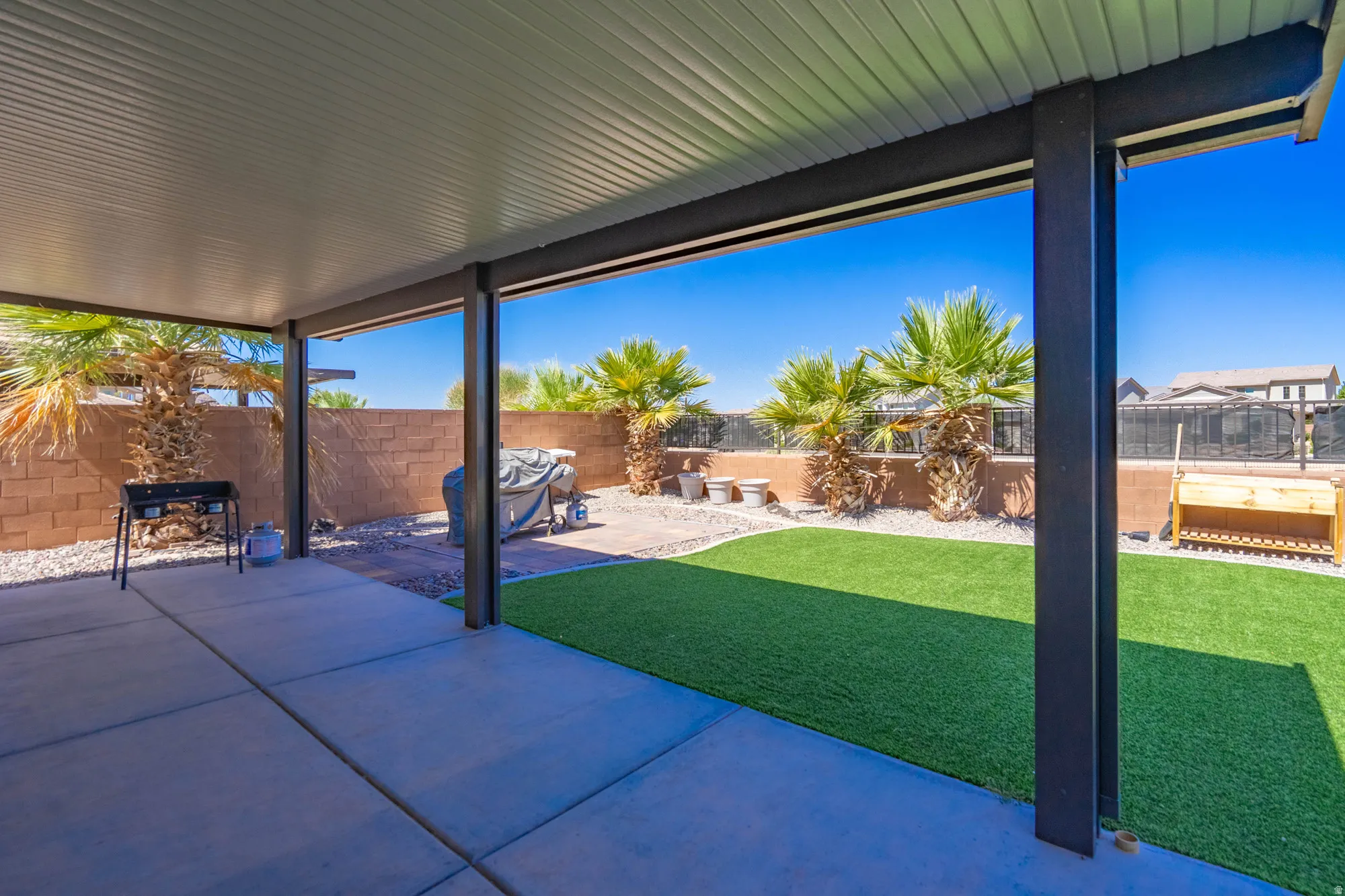 Expansive covered patio featuring concrete flooring, a solid roof, and structural support beams