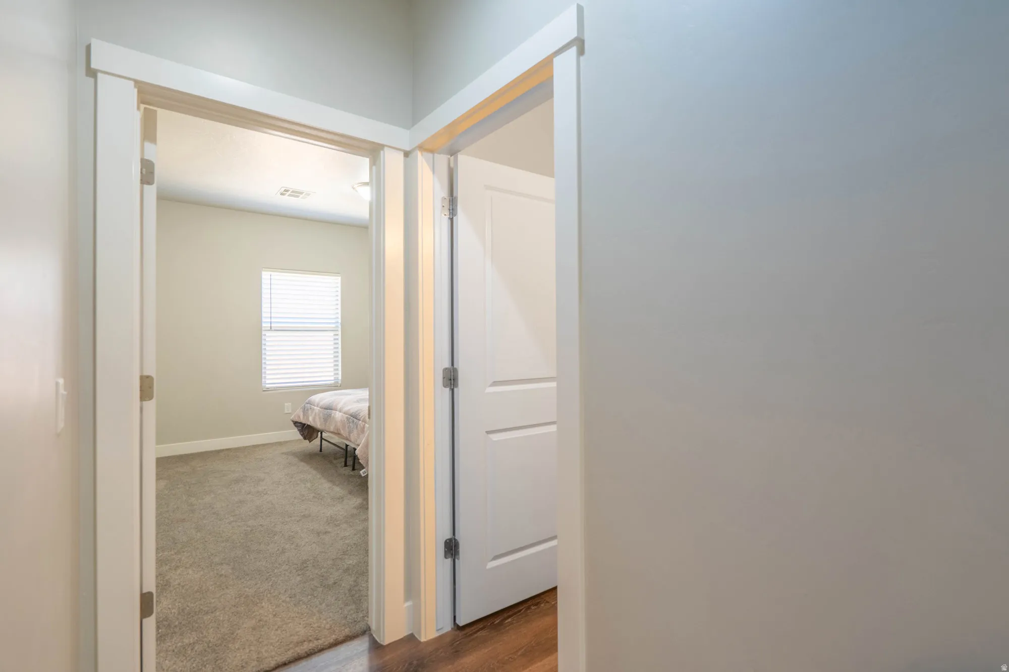 Bedroom featuring a window with horizontal blinds, neutral-toned walls, and carpet flooring