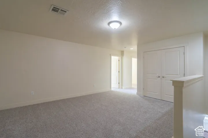 Carpeted room with a flush-mount ceiling light, white baseboards, and a double-door closet