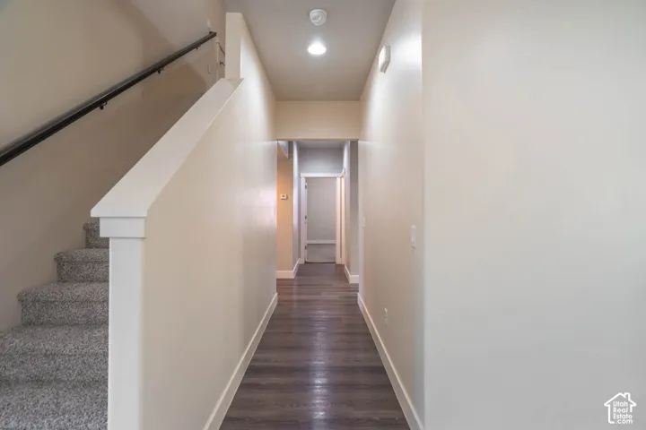 Entryway featuring wood-finish flooring, recessed lighting, and a carpeted staircase with a dark railing