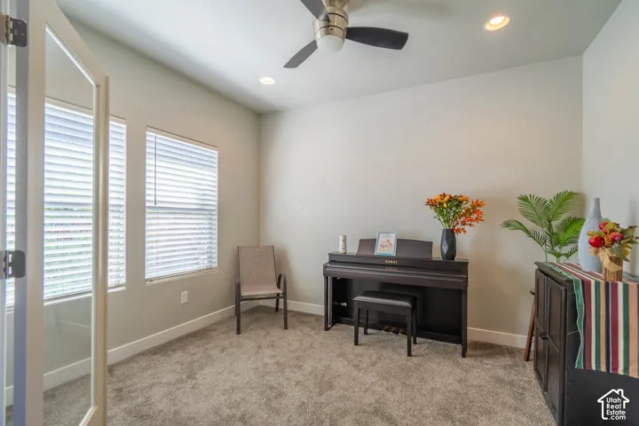 Carpeted interior room featuring a ceiling fan with integrated lighting, recessed lighting, and two windows with blinds