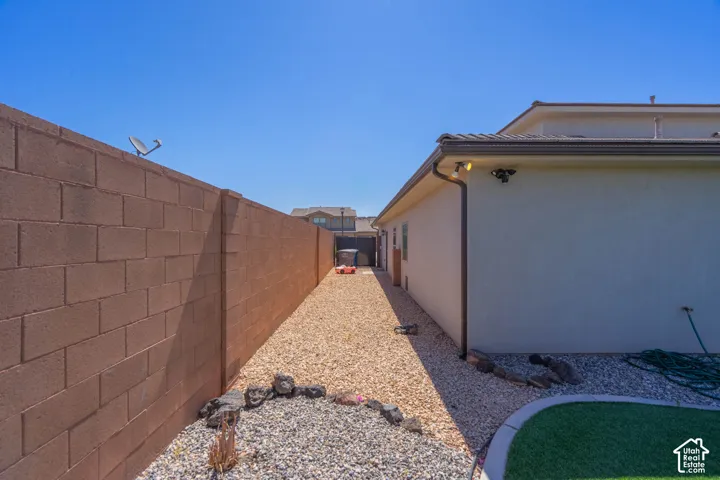 Side yard featuring a gravel pathway, stucco exterior, and concrete block wall