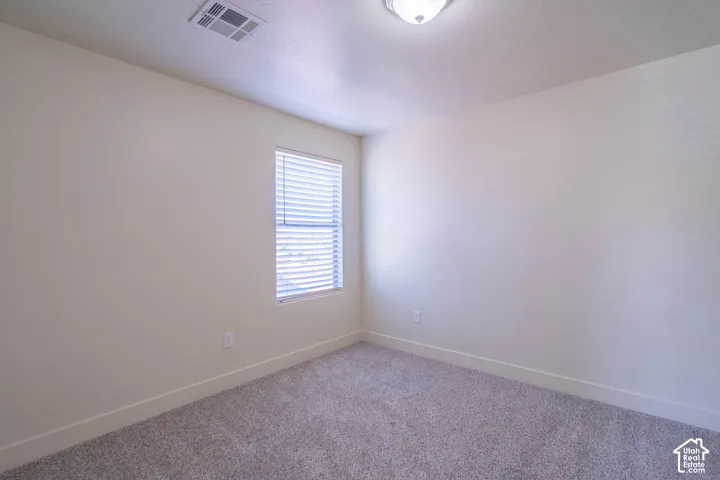 Interior room featuring neutral wall paint, grey carpet flooring, a window with horizontal blinds, and a flush mount ceiling light fixture