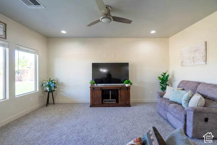Spacious living area featuring light-toned walls, recessed lighting, and a ceiling fan with integrated lighting